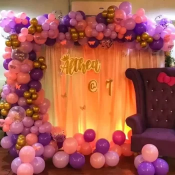Bright balloon backdrop for a birthday with a stylish purple chair and a lit curtain, ideal for a children's party, arranged by HKGN Tent House & Decoration, tent hire service in Hyderabad.